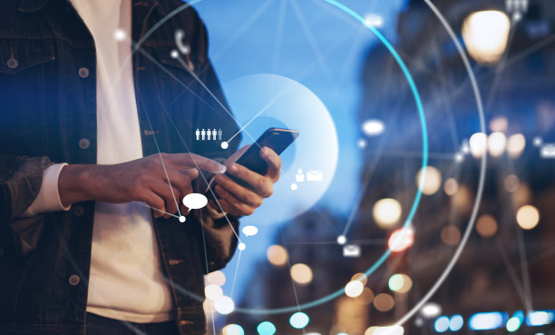 这是一个男性手拿着智能手机的特写照片，晚上在城市街道上搜索互联网或社交网络，嬉皮士在聊天中输入短信图片下载