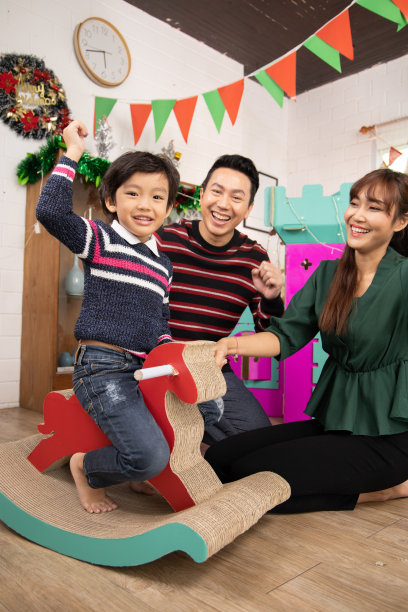 可爱的孩子们玩而父母在家里一起放松，微笑活跃的男孩娱乐纸玩具，摇摆马，幸福的家庭一起在客厅度过周末时间。亚洲家庭幸福时光的概念。图片下载