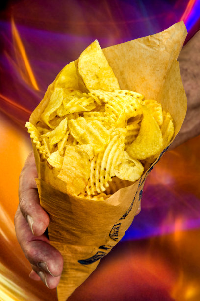 一个手拿着油炸槽薯片在纸袋的特写图片下载