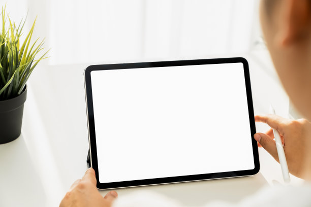 女人的手握着数字平板电脑的特写在桌子上，屏幕是空白的。图片下载