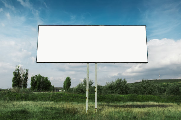 在蓝天的背景下，在绿色的田野中，为广告海报的空广告牌。图片下载