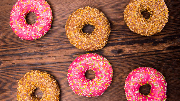 釉面甜甜圈与粉色巧克力糖霜与点缀在木制背景，文字空间，近距离图片下载