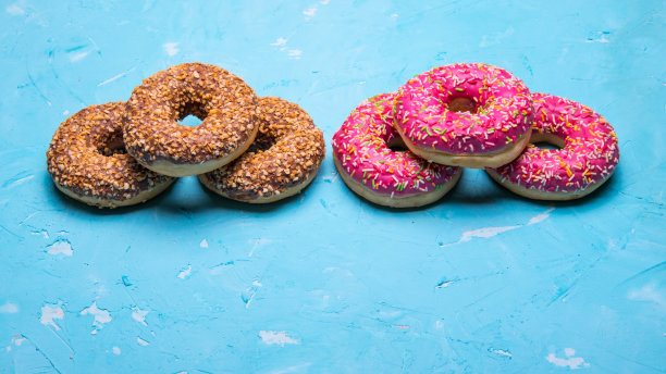 釉面甜甜圈与粉色和巧克力糖霜与点缀在蓝色背景，文字空间，特写图片下载