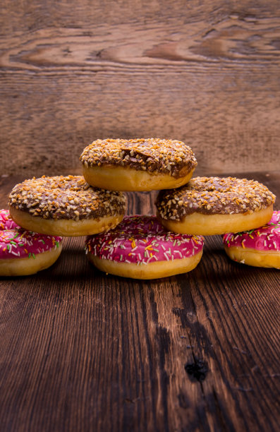 釉面甜甜圈与粉色巧克力糖霜与点缀在木制背景，文字空间，近距离图片下载