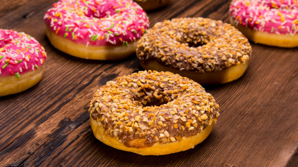 釉面甜甜圈与粉色巧克力糖霜与点缀在木制背景，文字空间，近距离图片下载