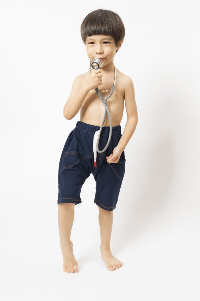 亚洲男孩微笑着，在白色背景上玩听诊器。图片下载