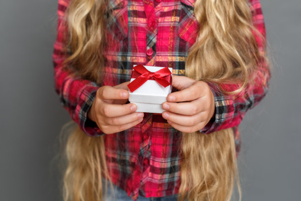 小女孩孤立地站在灰色与礼品盒的特写图片下载