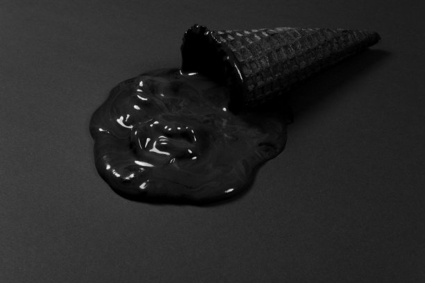 “黑色星期五”的概念。在黑色的背景上，蛋卷上融化的黑色冰淇淋。图片下载