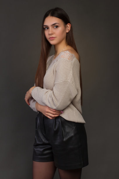 年轻漂亮，黑发长发，侧身站在镜头前。在一个工作室照片在黑暗的背景在暖色图片下载