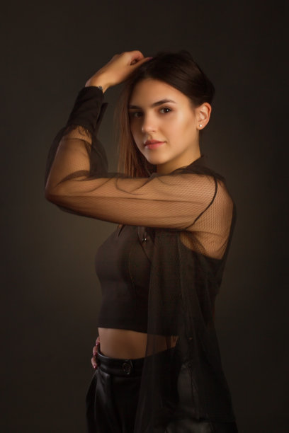 年轻美丽的黑发长发，摆着黑色的衣服。摄影棚里的照片图片下载