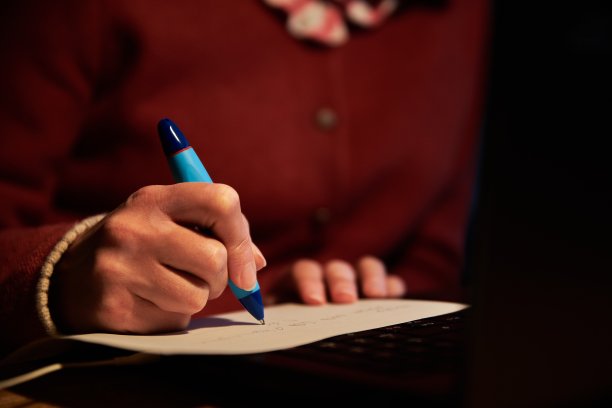 一个人做笔记的特写。一个人在工作桌上工作在晚上的特写。图片下载
