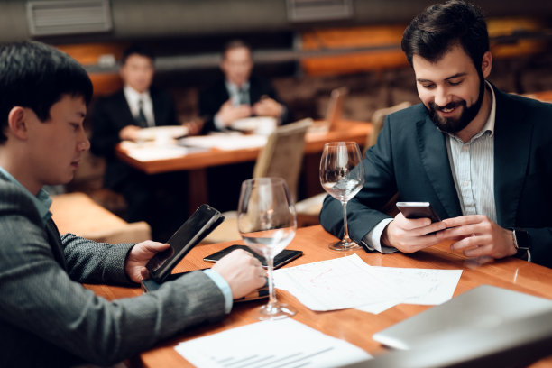 在饭店会见中国商人。男人都在看手机。图片下载