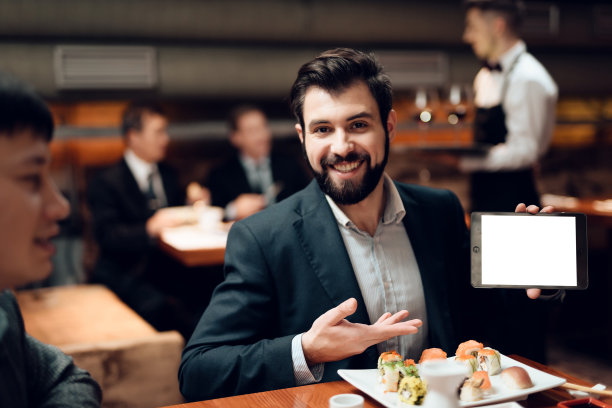 在饭店会见中国商人。男人正在展示平板电脑。图片下载