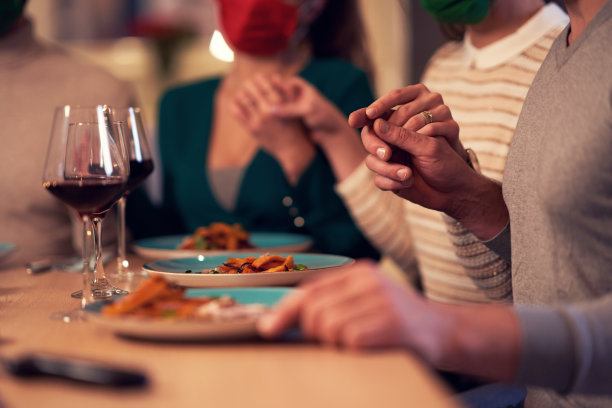 一群戴面具的朋友在家里的圣诞感恩节餐桌上祈祷图片下载