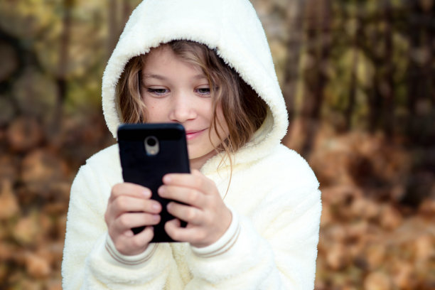 美丽的女孩和她的手机在秋天图片下载