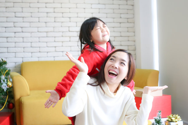 新年快乐。妈妈给孩子们礼物。可爱的女孩给他心爱的妈妈一个礼物。妈妈和女儿在圣诞节是快乐的。图片下载