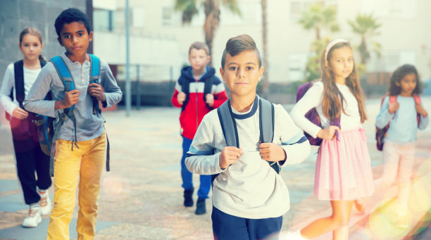 正面的男孩站在学校附近，背景是孩子们图片下载
