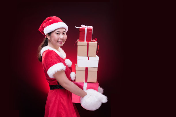 在圣诞快乐和新年快乐之际，一个穿着圣诞老人服装的美丽女人带着许多礼盒图片下载