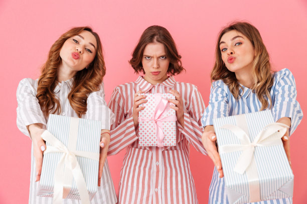 照片上，20多岁的黑发女友穿着休闲装，在开心的过夜时拿着礼物盒，孤立在粉红色的背景下图片下载