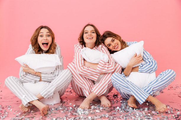 照片中，20多岁的睡意朦胧的女性穿着休闲服装坐在地板上，双腿交叉，抱着枕头，在粉红色的背景下与世隔绝图片下载