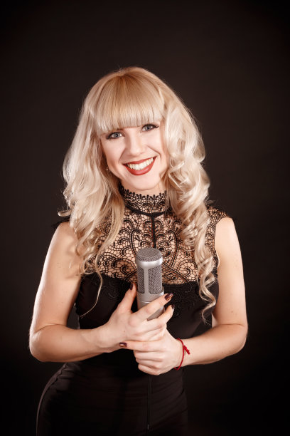 用复古麦克风唱歌的女人。美丽魅力歌手女孩肖像。在黑色的背景。复古风格。卡拉ok歌曲图片下载