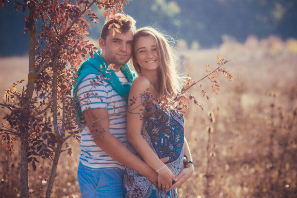 一对幸福的年轻夫妇怀上了孩子，怀孕的女人用丈夫抚摸着肚子。图片下载