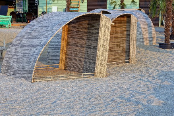 开放的棕色木制帐篷矗立在海滩的灰色沙滩上图片下载