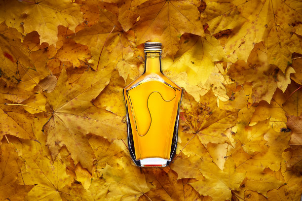 黄色枫叶上的白兰地酒瓶图片下载
