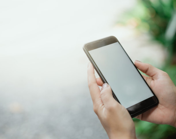 使用智能手机的手图像，模糊的背景图片下载