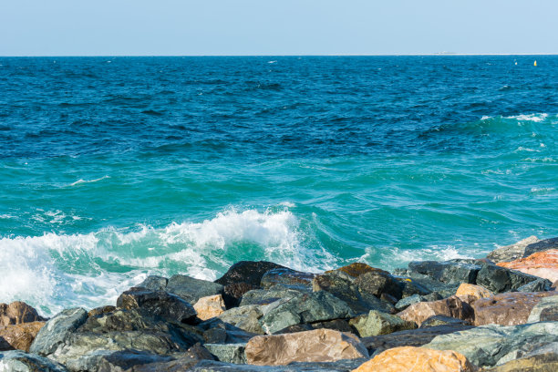阿拉伯联合酋长国迪拜朱美拉棕榈岛新月路，波斯湾海浪拍打着防波堤的石头图片下载
