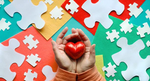 4月2日世界关爱自闭症日的创意设计。平躺着，双手捧着红石心图片下载