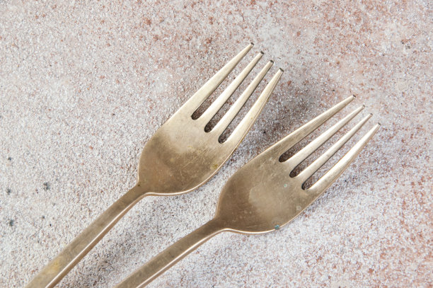 混凝土背景上的两个古老的青铜叉子。图片下载