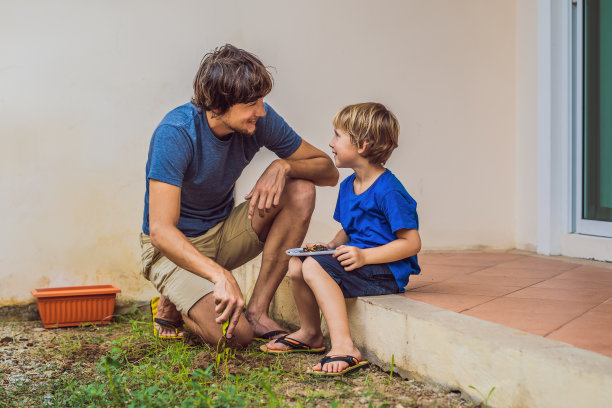 父亲和儿子在房子附近的花园里种花图片下载