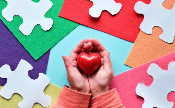 4月2日世界自闭症日创意设计。全景感知旗帜，手握红心图片下载