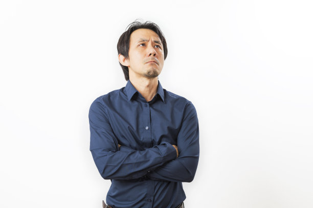 中年亚洲男子在一件黑色的衬衫和眼镜与好奇的表情。图片下载