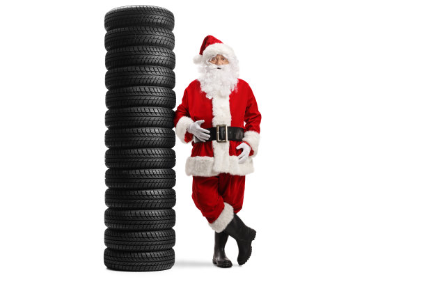 完整的圣诞老人肖像倚在一堆汽车轮胎孤立在白色的背景图片下载