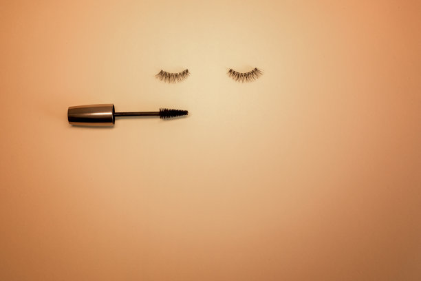 假睫毛和一个橙色背景和复制空间的睫毛膏棒。图片下载