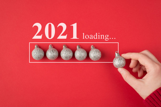 圣诞节即将来临的概念。剪近景照片的手拿着小银光与闪光球树玩具放在一条线孤立的充满活力的颜色红色背景图片下载