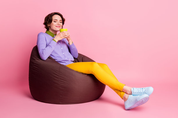 全长侧面照片的女孩坐棕豆椅子闻咖啡杯香气孤立的粉红色背景图片下载