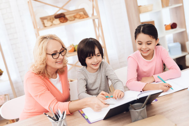 祖母帮助给孙辈们上课。美丽的奶奶帮助孩子们学习。图片下载