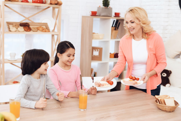 小孙子们坐在厨房里等着漂亮的奶奶端来晚餐。图片下载