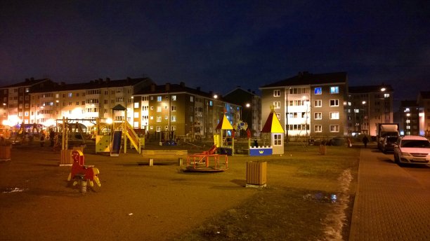 孩子们晚上在新住宅楼附近的户外游乐场。没有人。舒适安全的城市环境。真实的城市生活。呆在家里的概念。房子窗户上的灯光。晚上图片下载