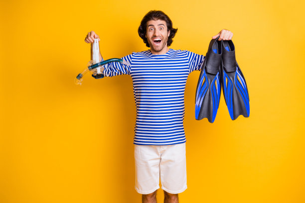 照片惊讶的家伙拿着浮潜装备鳍呼吸面罩护目镜穿短裤连衣裙孤立在黄色背景图片下载