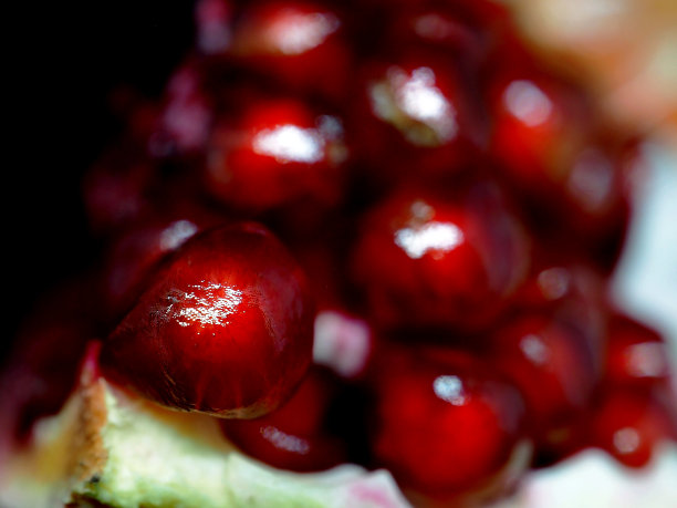 把红色的石榴切成薄片放在黑色的背景上图片下载