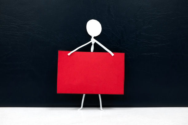 一个棍棒人的数字持有空白的红色布告或通知或公告板在黑色的背景。行动主义，抗议，示威，社会运动和自由表达的概念模板。图片下载