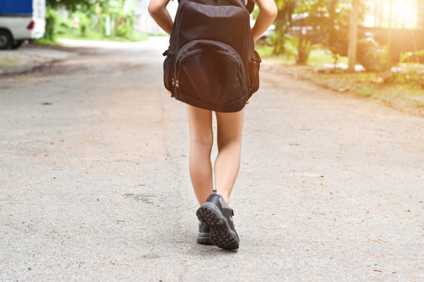回到学校。学生女孩背着背包步行去学校。图片下载