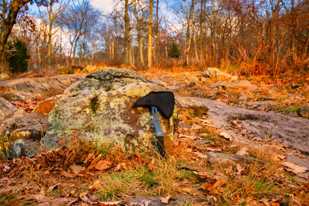 在秋天的田野里，投掷的斧头倚在一块岩石上图片下载