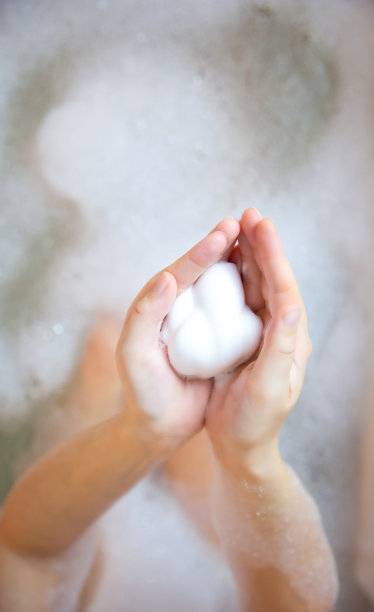 特写女人的手与洗发水或剃须肥皂泡沫与泡沫浴。美容保健理念俯视图图片下载