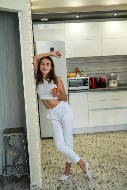 年轻女子的肖像站在桌旁，厨房里有新鲜的水果图片下载