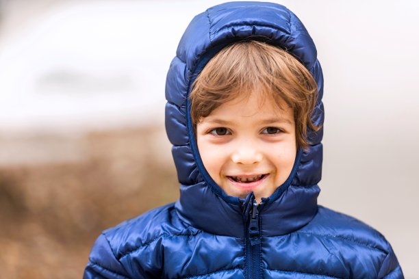 小男孩穿着一件冬衣，微笑着看着相机图片下载